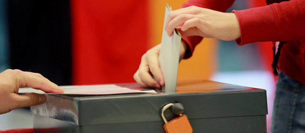 Eine Frau wirft ihren Wahlzettel in eine Wahlurne.
