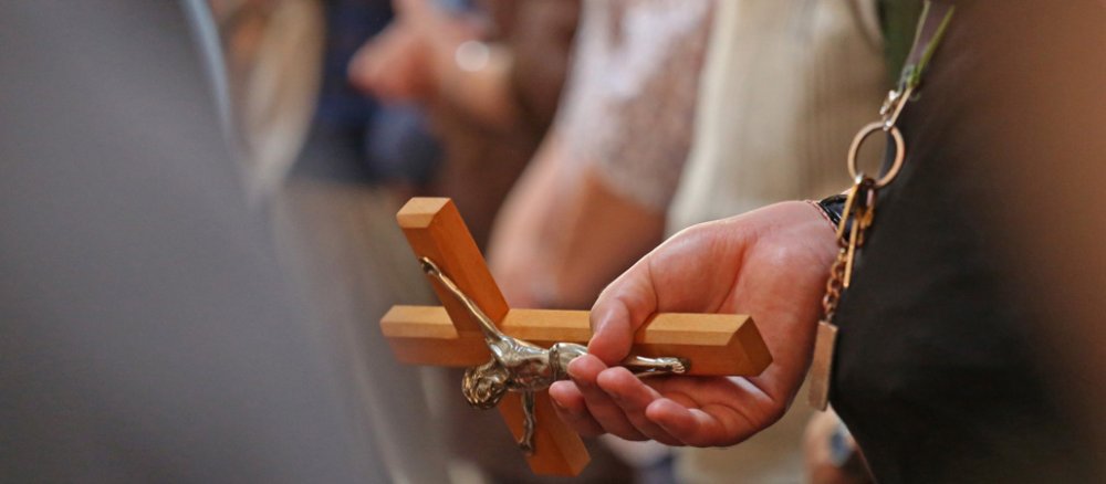 Eine Hand hält ein Kreuz.