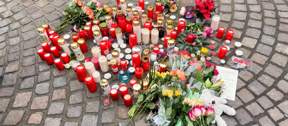 Kerzen und Blumen auf Kopfsteinpflaster