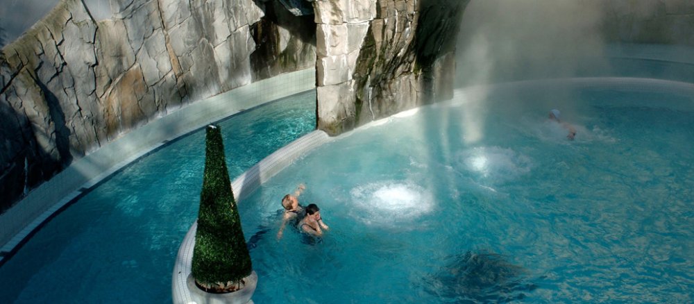 Ein Außenbecken mit Wasserfall in einer Therme