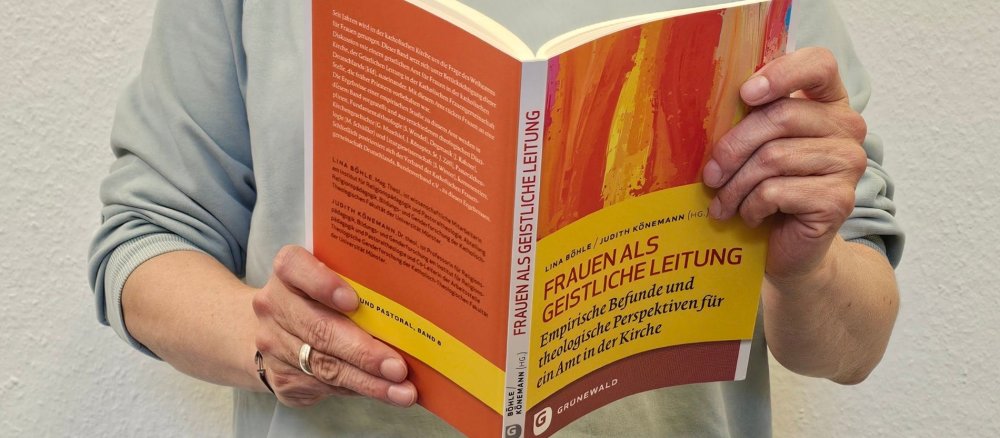 Eine Frau hält das Buch "Frauen als Geistliche Leitung" in den Händen