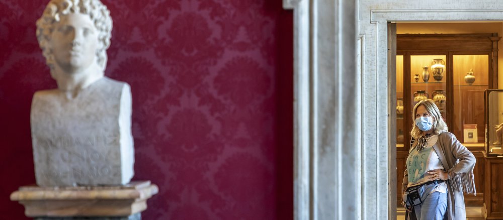 Eine Museumsbesucherin mit Mundschutz schaut auf eine Skulptur