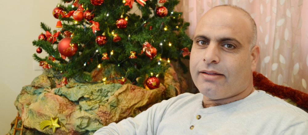 Hani Farah, Projektleiter des YMCA in Gaza sitzt vor einem Weihnachtsbaum.