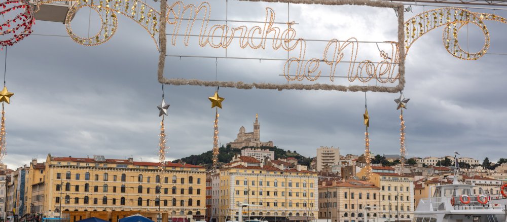 Ein Schild mit der Aufschrift Weihnachtsmarkt auf Französisch vor dem Hafen von Marseille