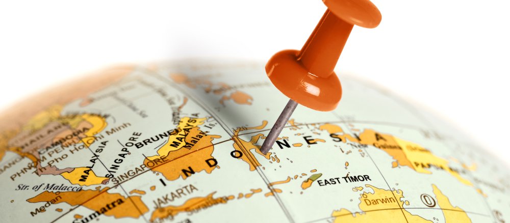 A pin is stuck in a globe at the level of Indonesia.