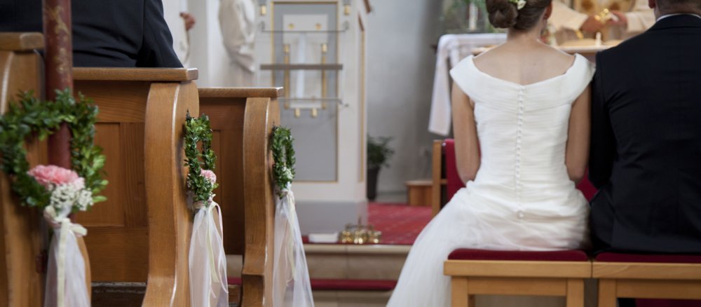Ein Brautpaar sitzt vor dem Altar.