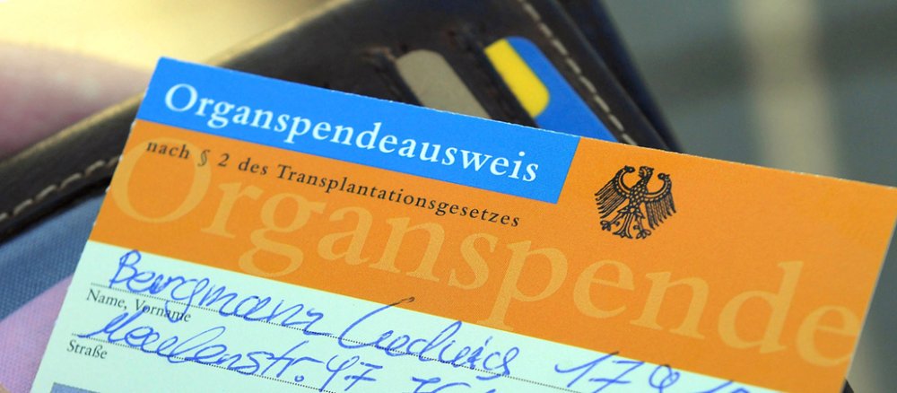 Ein ausgefüllter Organspendeausweis wirdaus einem schwarzen Geldbeutel geholt.