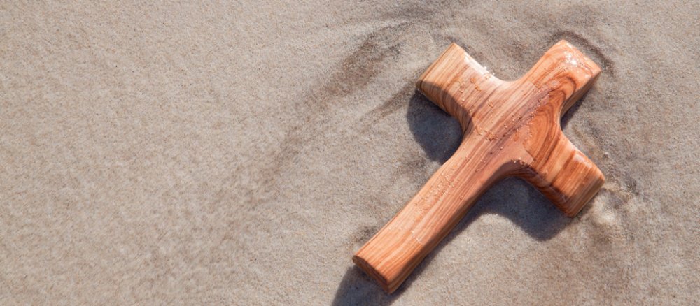 Ein Holzkreuz im Sand.