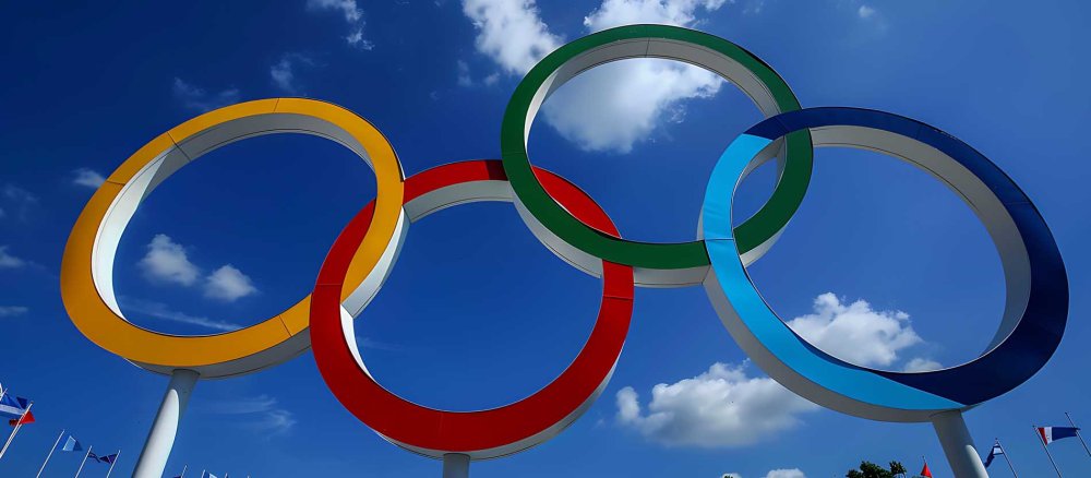 Die Olympischen Ringe vor blauem Himmel.