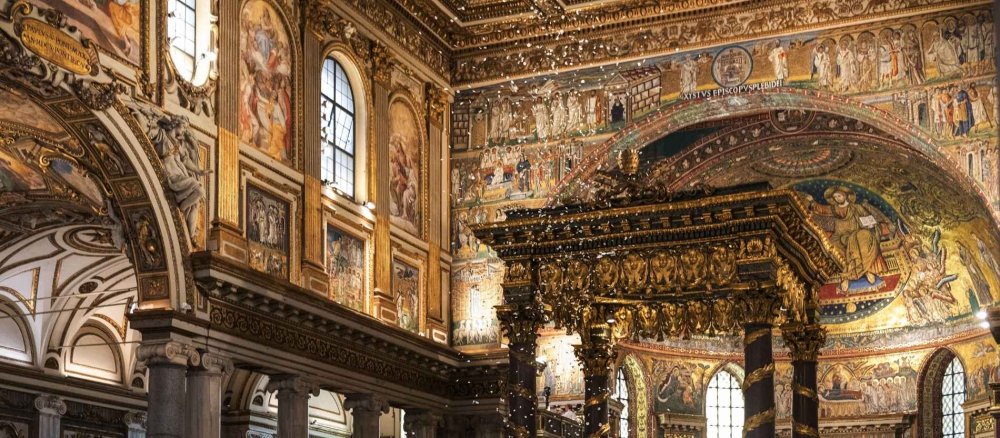 Weiße Blütenblätter rieseln von der vergoldeten Kassettendecke der Basilika Santa Maria Maggiore