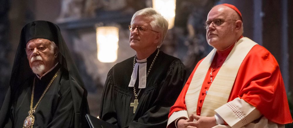 Drei Kirchenmänner unterschiedlicher Konfessionen sitzen in einer Reihe