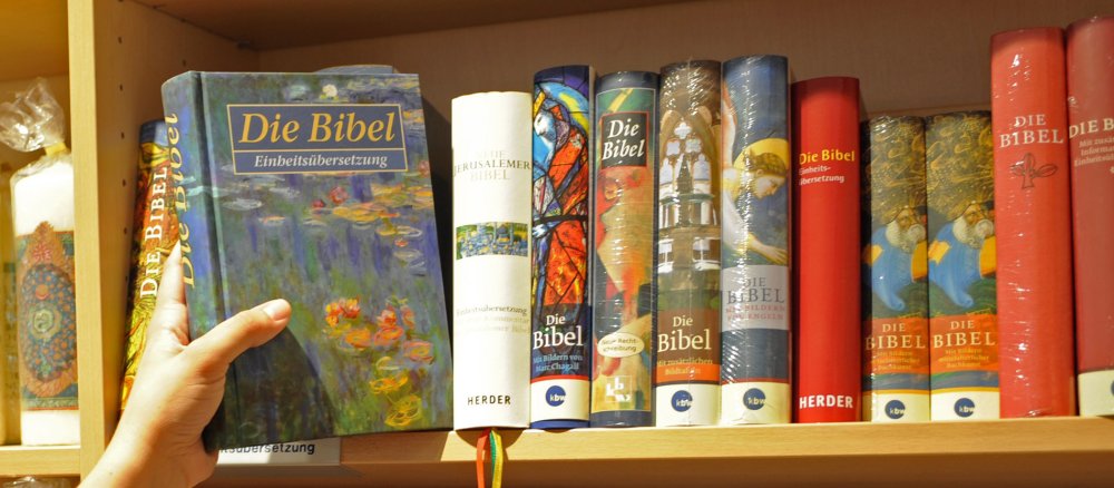 Eine Hand greift nach einer Bibel im Regal.