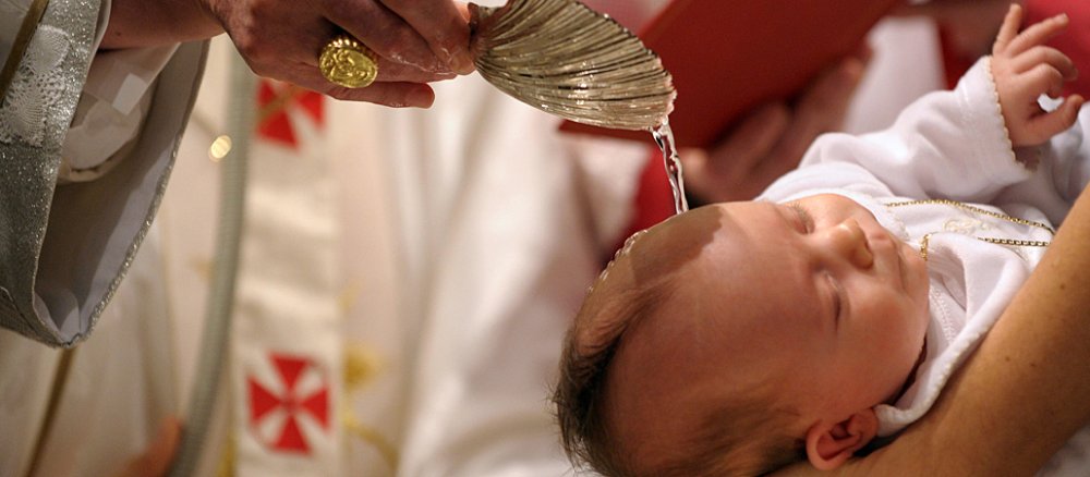 Papst Benedikt XVI. tauft während einer Messe in Rom ein Kind.