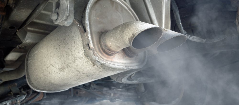 Dreckiger, qualmender Auspuff eines alten Autos