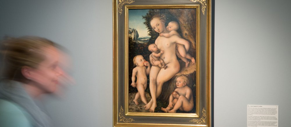 Ein Bild einer nackten Frau mit vielen Kindern hängt an der Wand.
