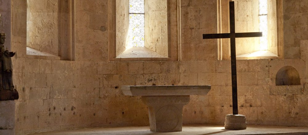 Ein schlichter Altar und ein schlichtes Kreuz in einer Seitenkapelle.