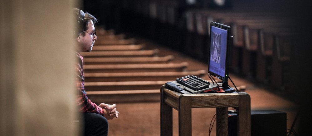 Man sits praying in front of a screen