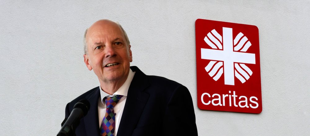 Caritasdirektor Heinz-Josef Kessmann vor dem Logo der Caritas