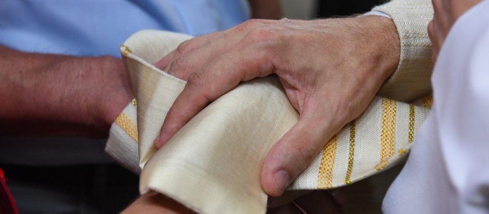 Ein Priester legt seine Stola um die Hände eines Paares