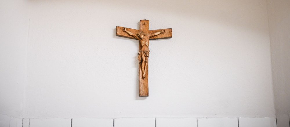 Ein Kruzifix aus Holz hängt an einer weißen Wand