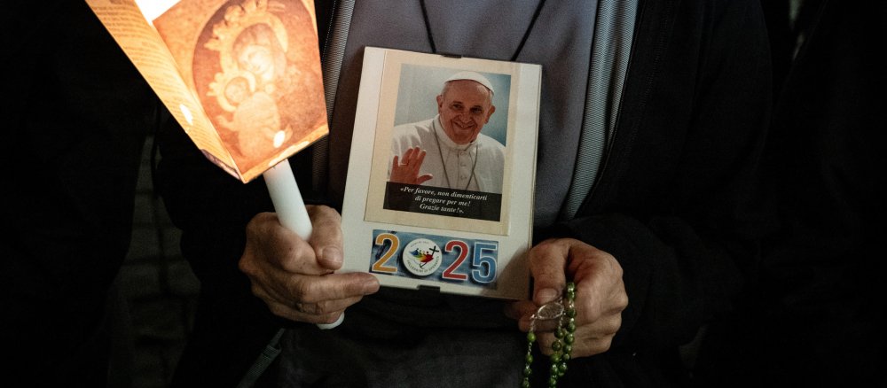 Eine Ordensfrau hält ein Bild von Papst Franziskus bei der Rosenkranzandacht für den erkrankten Papst