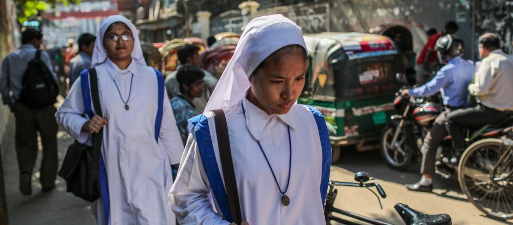 Missionarinnen der Nächstenliebe, auch Mutter-Teresa-Schwestern genannt, durch eine belebte Straße in Dhaka in Bangladesch.