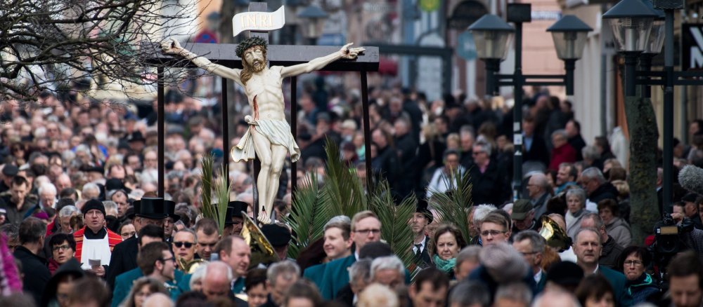 Gläubige tragen bei der Heiligenstädter Palmsonntagsprozession eine Darstellung des gekreuzigten Jesus