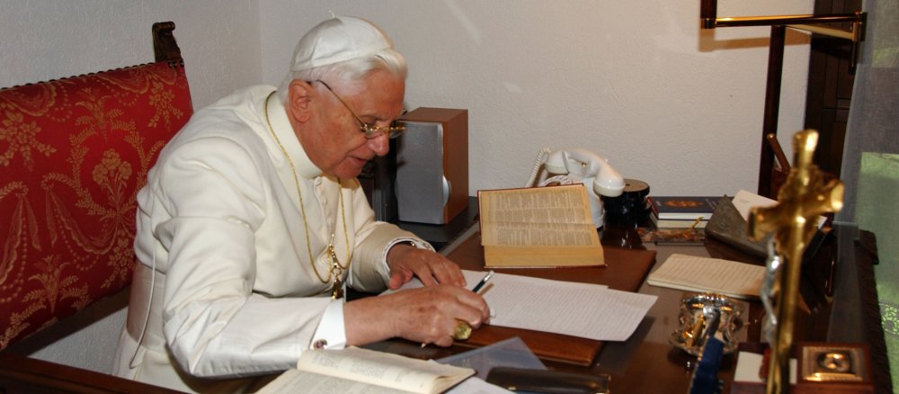 Papst Benedikt XVI. sitzt an seinem Schreibtisch und arbeitet an einem Text.