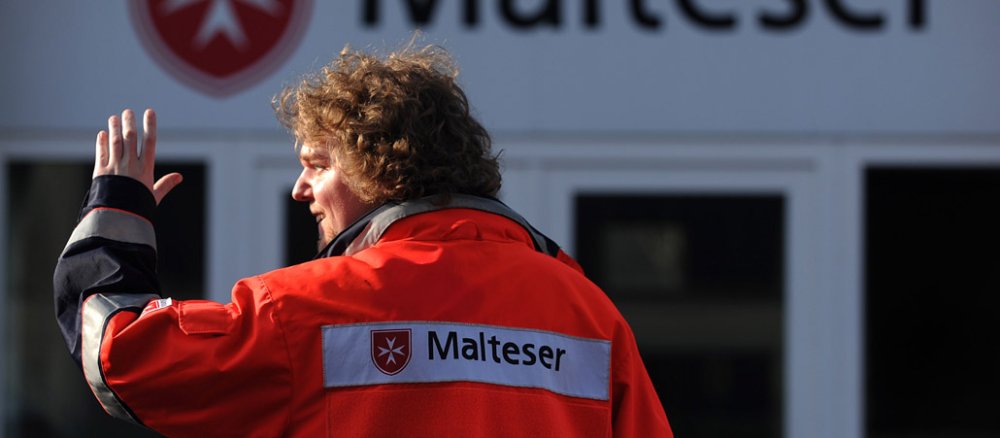 Ein Mann trägt die Uniform der Malteser.