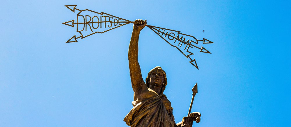 A statue holds up the words "Droits de l'homme - Human Rights"