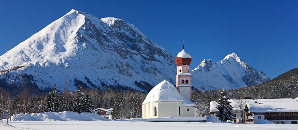 Die Pfarrkirche im Ortsteil Kirchplatzl von Leutasch in Tirol liegt direkt am Fuße der Hohen Munde (2662m).