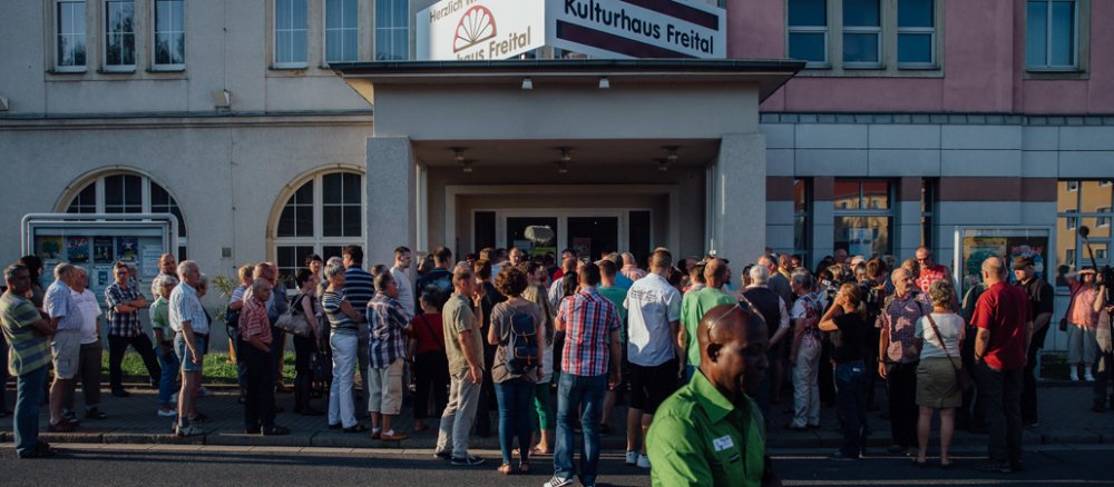 Menschen stehen vor dem Kulturhaus Freital Sachsen in einer Schlange.
