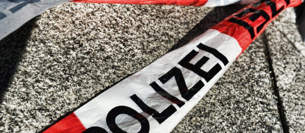 Ein rot-weißes Absperrband der Polizei liegt auf dem Boden.