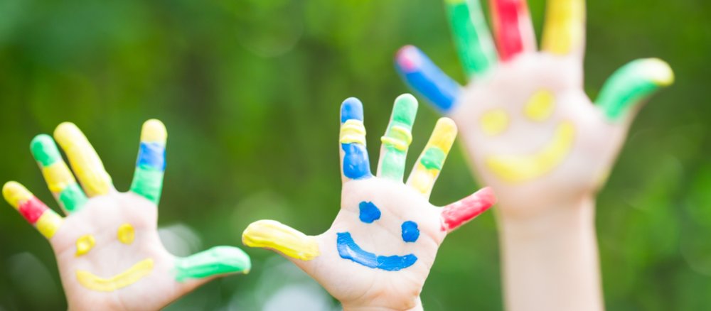 Bunt bemalte Kinderhände recken sich in die Luft