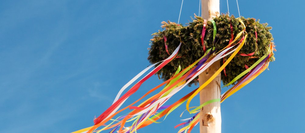 Ein traditioneller Maibaum vor blauem Himmel.