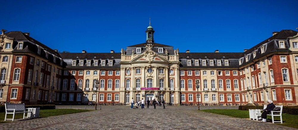 Blick auf das Schloss in Münster, vor dem Studentinnen gehen