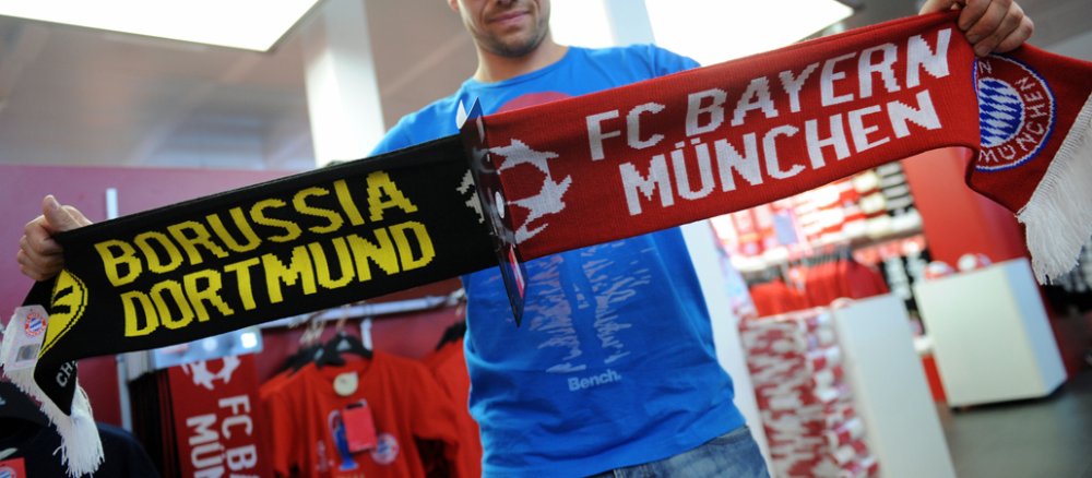Ein Fan des Fußball-Bundesligisten FC Bayern München hält am 16.05.2013 im FC Bayern Fanshop in München (Bayern) einen Schal mit den Namen der beiden Finalgegner in Händen.