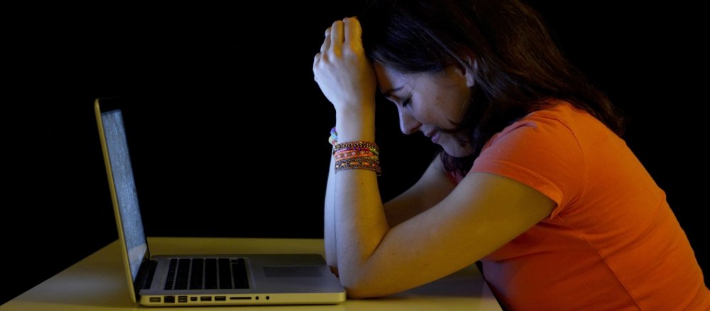 Eine Frau sitzt vor einem Laptop und weint