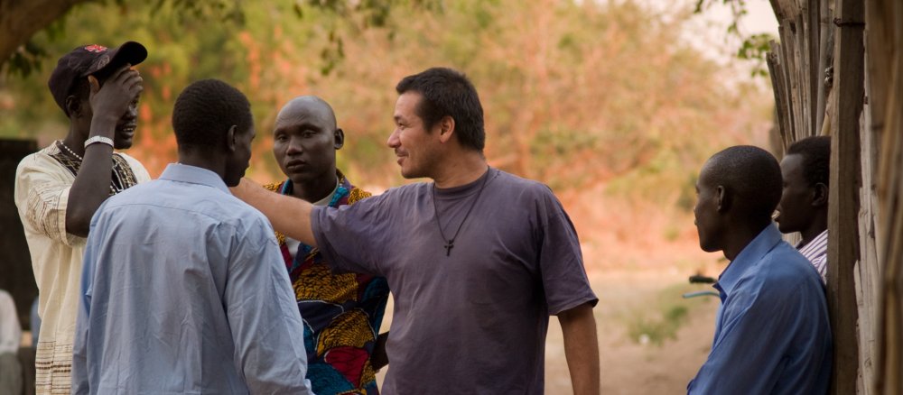 Der Comboni-Missionar Gregor Schmidt steht in einer Gruppe afrikanischer Männer.