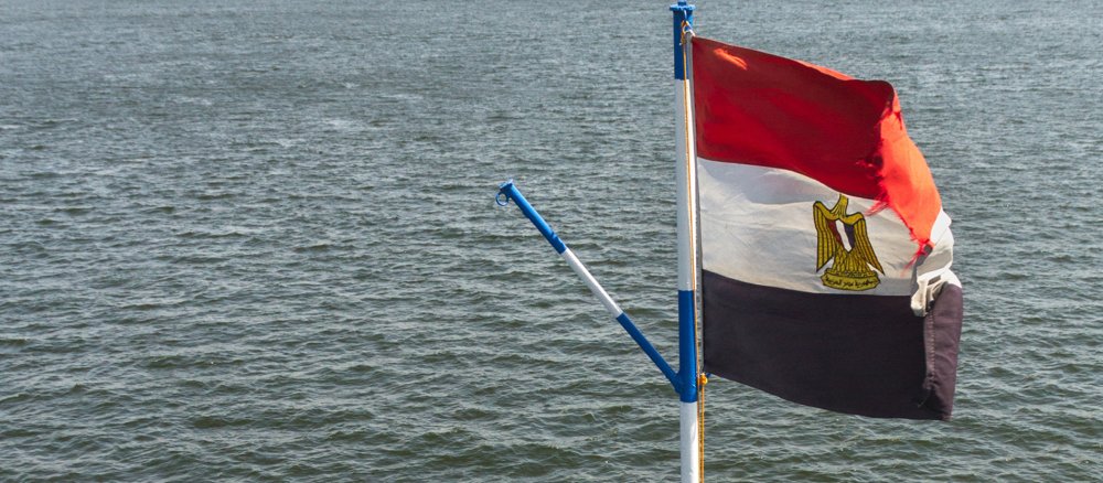 Eine Flagge von Ägypten flattert über dem Nilwasser.