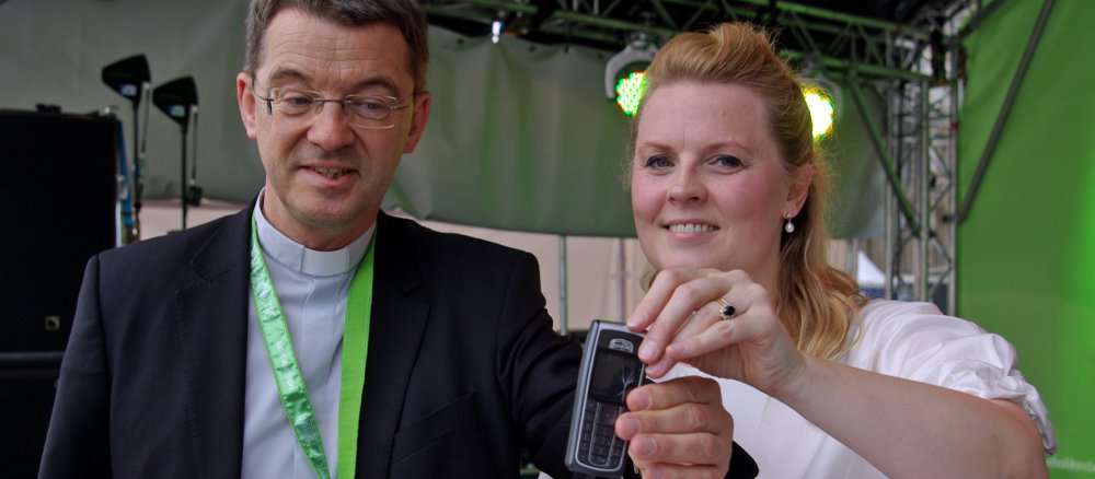 Patricia Kelly und Prälat Klaus Krämer werfen ein Handy ein.
