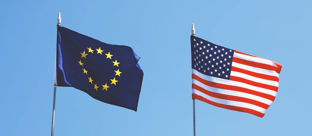 Eine Flagge der EU und eine Flagge der USA flattern nebeneinander im Wind
