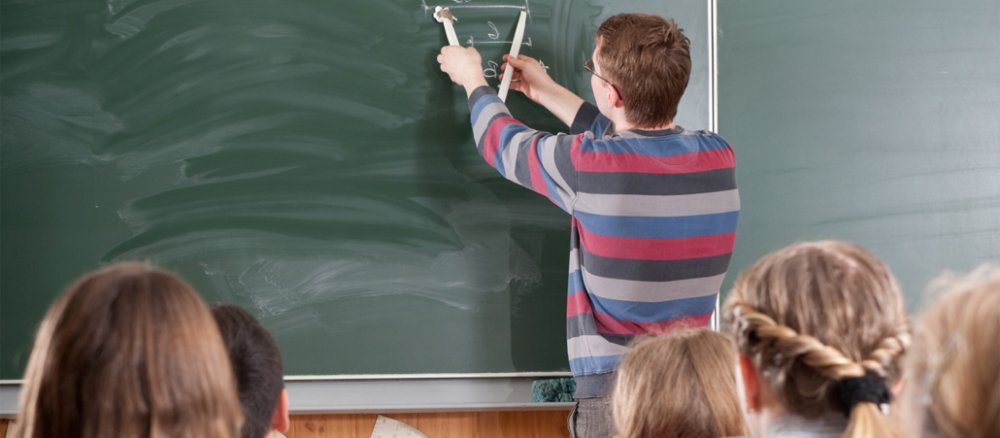 Lehrer mit Zirkel an der Tafel