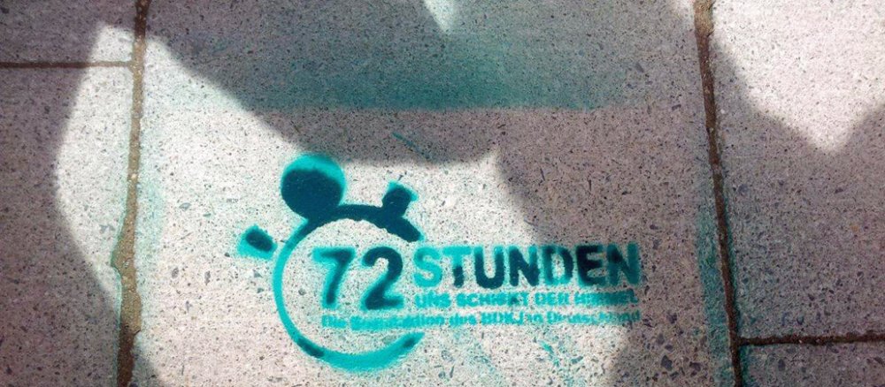 Logo der 72-Aktion auf einer Straßen in München.