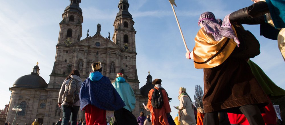 Als Könige verkleidete Kinder laufen über einen Domplatz