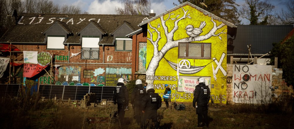 Polizisten stehen vor einem mit Graffiti beschmierten Gebäude in Lützerath.