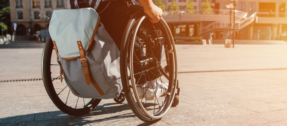 Ein Rollstuhlfahrer ist mit einem Rucksack in der Stadt unterwegs