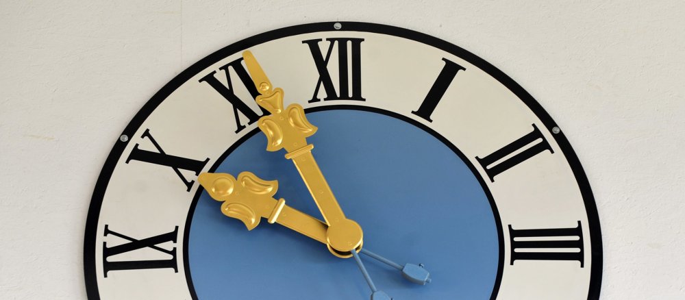 Nahaufnahme einer Uhr mit römischen Ziffern und goldenen Zeigern