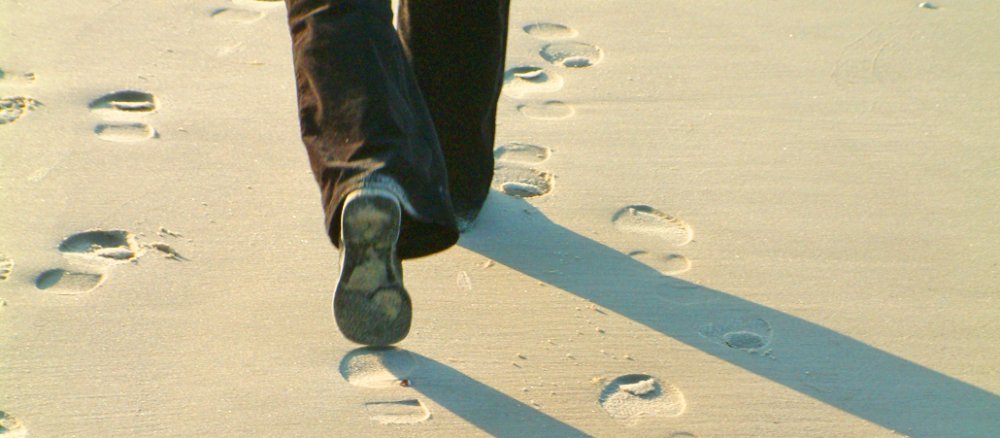 Füße hinterlassen Spuren im Sand.