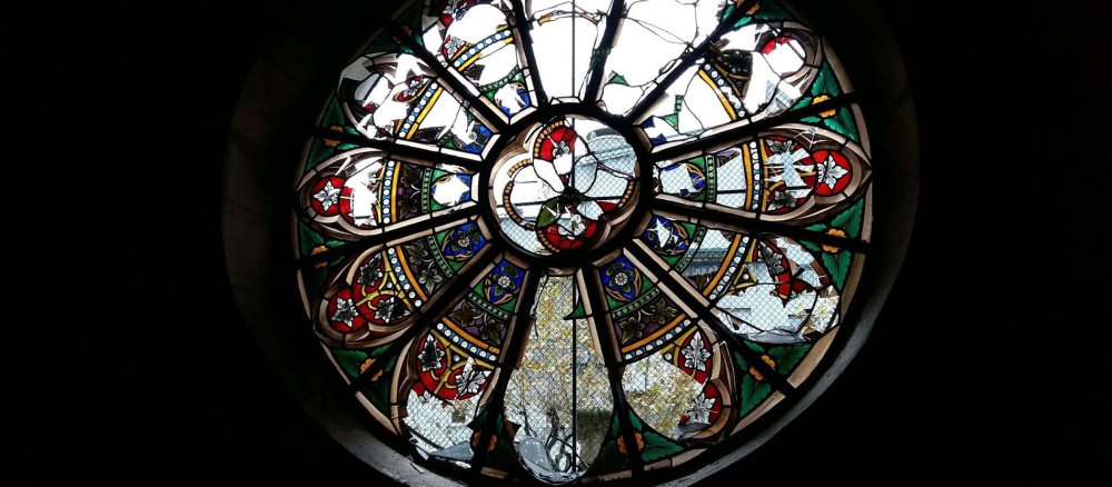 Das durch Steinwürfe zerbrochene Fenster einer französischen Kirche.